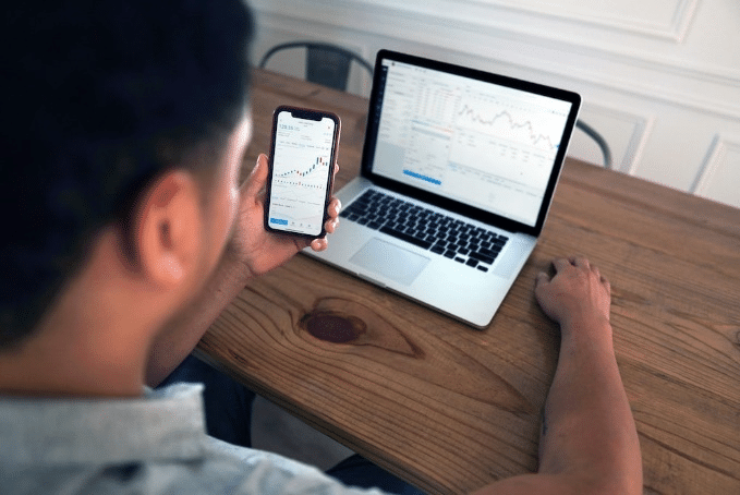 A person holding mobile near MacBook pro